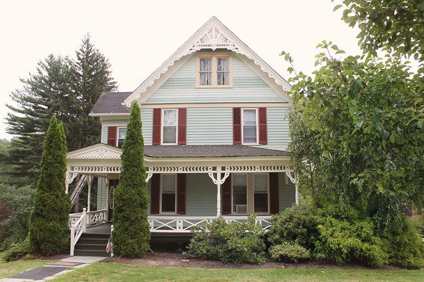 Light green Victorian res hall with red shutters.